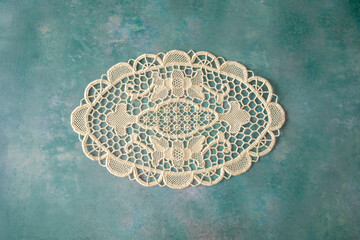 A single lacy doyley shot from above on a green textured background, space for text