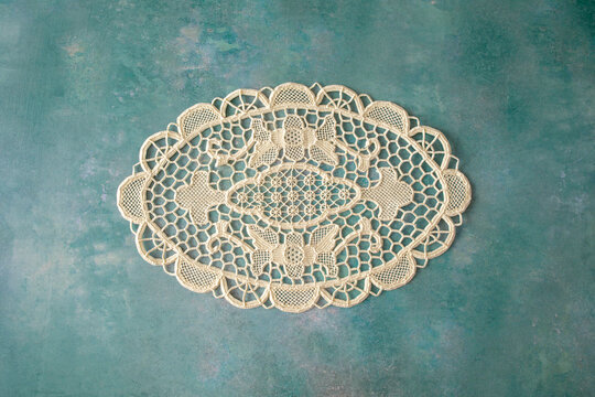 A single lacy doyley shot from above on a green textured background, space for text