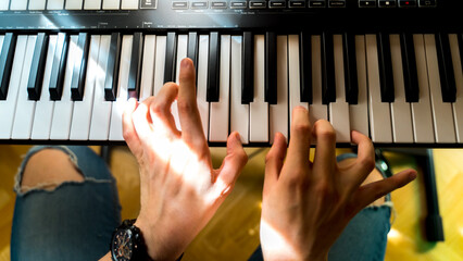 A close up of hands playing electric piano in home studio during the day