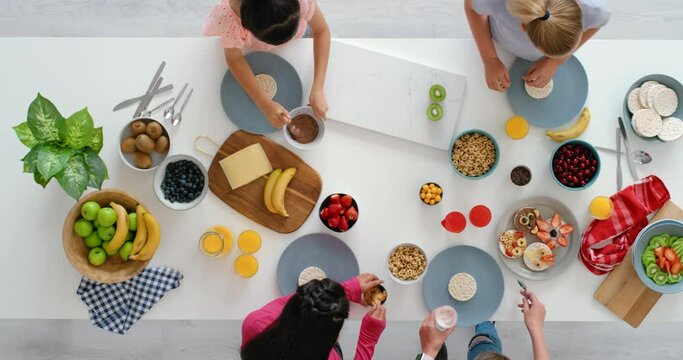 Healthy lunch and fresh diet for children together making delicious snacks on table from above. Overhead of young kids preparing a meal of rice cakes for nutrition with fruit nut butter and cereal