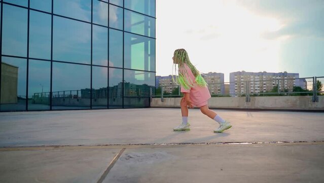 Girl dancing outdoors. Beautiful child with bright green afro hairstyle express emotions in dance. Young professional dancer improvise in freestyle. Youth culture concept. Slow motion 4k footage