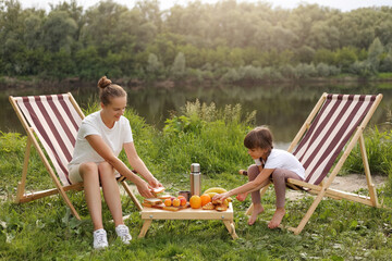 Full length portrait of attractive woman wearing white t shirt sitting on folding picnic chairs...