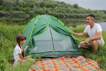 Portrait of happy handsome man wearing casual clothing posing near green tent with his cute...