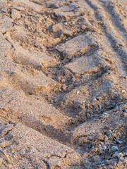 Background texture of a tire track on a sandy beach. The texture of sand on the beach with a trace of tread close-up. Sandy textured background