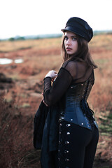 Color vivid photo of a beautiful brunette in a gothic outfit in a red wasteland in a...