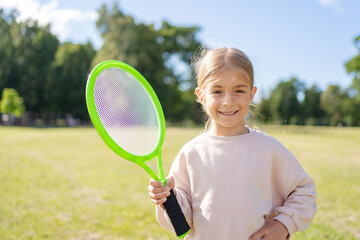 Little girl during tennis training or workout. Preschooler playing badminton in sunny summer park.