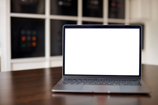 Mockup image of laptop with blank white desktop screen on a wooden table in an ordinary apartment. Laptop with blank screen for design. front view.