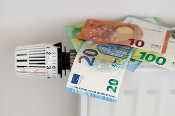 Euro money banknotes on the heating radiator with temperature control regulator. Expensive and...