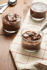 Creamy french chocolate ganache or pudding in glass on linen napkin on wooden background, three glasses