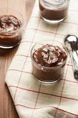 Creamy french chocolate ganache or pudding in glass on linen napkin on wooden background, three glasses