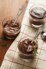 Creamy french chocolate ganache or pudding in glass on linen napkin on wooden background, three glasses