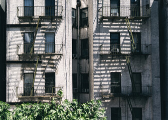 Facade of Manhattan old residential building with brick wall, shadow of fire escapes, New York. AC, air conditioning