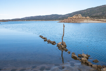 Obraz premium A submerged and weathered barbed wire fence enters the water of a lake.