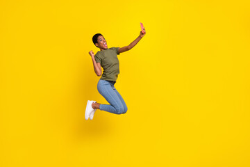 Fototapeta na wymiar Full size photo of delighted excited person raise fist jump take selfie photo isolated on yellow color background