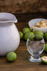 green walnut kernels leaves  wooden table oil nuts unripe husks healthy food drink, old rustic table Background Harvest, organic Homemade plant based milk Dairy free  jug glass cup