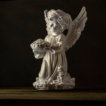 Guardian angel isolated black background statue copy space beautiful holy wings bowl of roses flower in hand