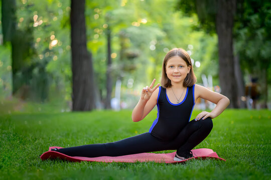 a little girl in the park performs stretching, stretching her squatting leg