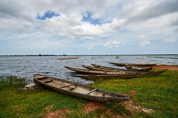 several fishing boats on the shore. wooden boats are pulled ashore with green grass. sky with white clouds