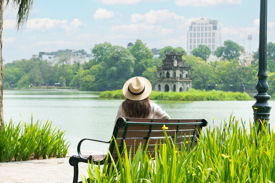 Woman traveller is sightseeing at Hoan Kiem Lake (Lake of the Returned Sword) and the Turtle Tower in Hanoi , Vietnam