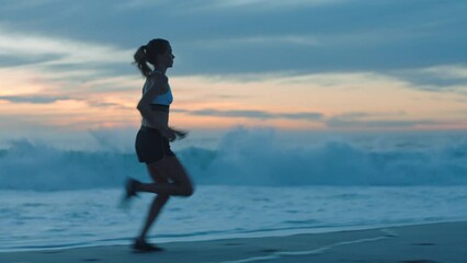 Active, fit and fast athlete running, jogging and sprinting on a beach at sunset. Shadow, outline and silhouette of a motivated woman with stamina doing workout, exercise and training by the ocean