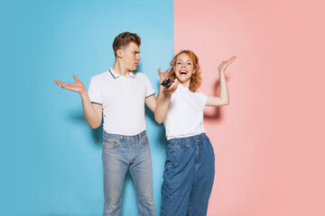 Portrait of young couple choosing movie to watch isolated over pink blue studio background. Disagreement