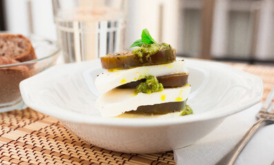 caprese salad with mozzarella, black tomatoes and pesto in white plate