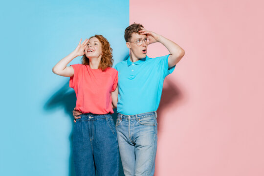 Portrait of young couple, man and woman in asual clothes posing isolated over pink blue studio background