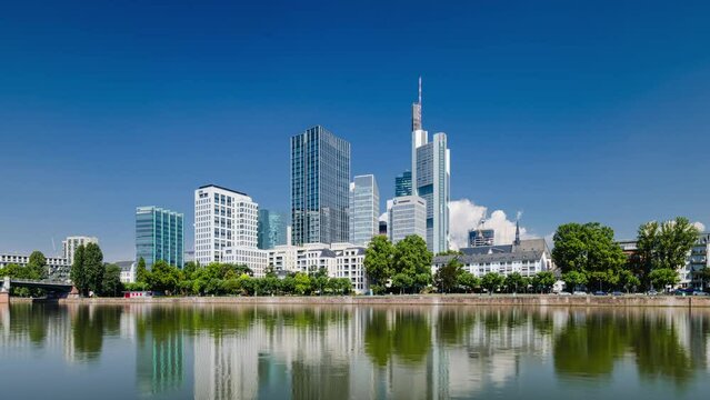 Frankfurt skyline time lapse, blue sky with clouds, office buildings and skyscraper in center with river in the foreground, Frankfurt am Main, Hessen, Germany