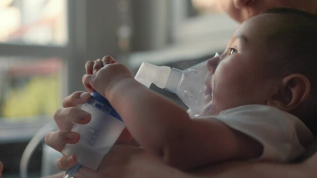 Side view of baby breathing an inhaler at home