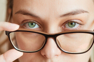 Close-up of a young woman taking off her glasses. Vision correction concept, spectacle frame