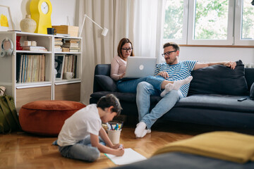 family with on kid relaxing at home using laptop computer