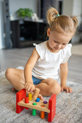 Cute caucasian little girl playing on the floor at home with eco wooden toys. The child playing educational games.