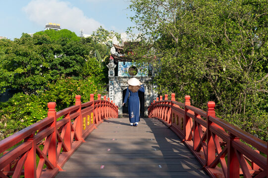 Woman traveller is sightseeing at Huc Bridge spanning Ngoc Son Temple, Hanoi, Vietnam
