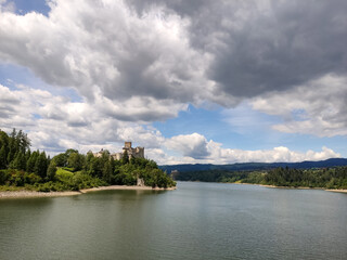 Fototapeta na wymiar Niedzica Castle Also Known as Dunajec Castle by Lake Czorsztynin the Pieniny Mountains, Poland. And Tourist Ferrys in the Lake. Summer Day With Fast Moving Clouds. Czorsztyn Castle at the Background