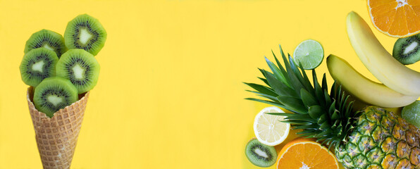Banner. Ice cream cone with chopped kiwi and tropical fruits on the yellow background. Copy...