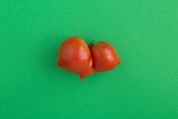 Ugly food. Tomato on the green background. Closeup. Top view.
