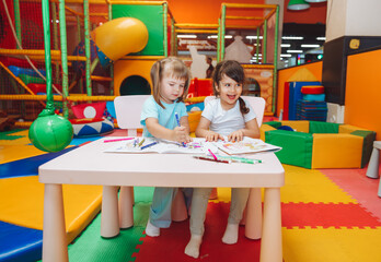 little girls are sitting at a table and drawing in a children's play center. children's creativity