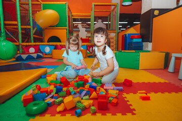 little girls are playing with a construction kit in the playroom. Preschool age.