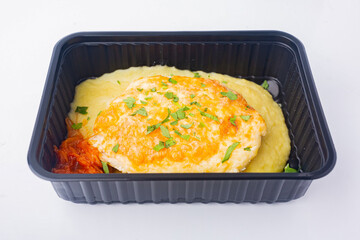 Food delivery to the office. Appetizing meat cutlet with mashed potatoes with caviar and onions in a disposable bowl