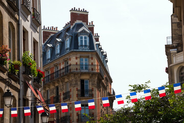  Parisian street decorated with French flags garland for Bastille Day on 14 July. Happy National holiday celebration concept. Paris, France. 