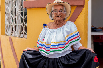 Elderly peasant woman wearing a typical Colombian costume and raising her long dress while looking...