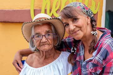 Portrait of old peasant woman with her smiling daughter, wearing typical Colombian clothes. Women...