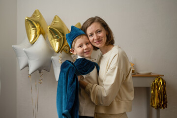 Mother holding little boy dressed up in a blue cap