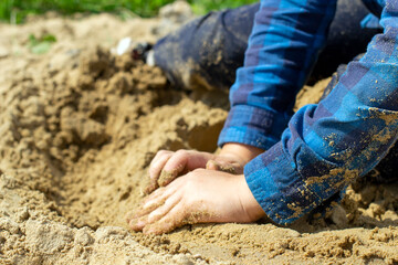 Hands of a child playing in the sand