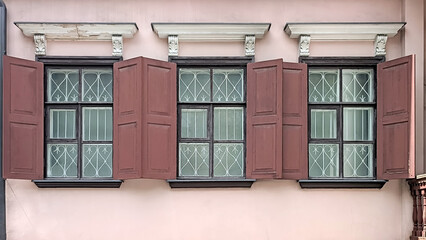 Three windows with shutters on the old building wall