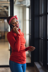 Portrait of smiling african american businesswoman talking on smart phone in creative office