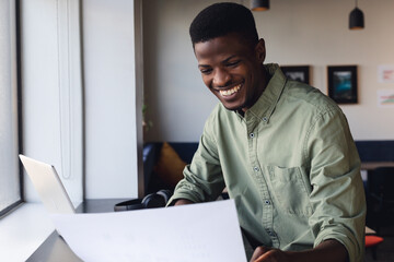 Smiling african american young businessman examining document in office