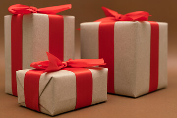 Close-up brown paper gift box red bow ribbon brown background. concept for happy love gift