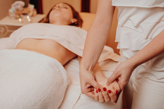 Beautician massaging hand of female in the spa salon, lifestyle and healthcare concept