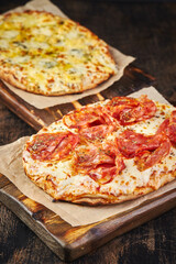 Two Roman-style pizzas with cheese and bacon. Roman square pizza or Pinsa on a thick dough, Italian Cuisine
